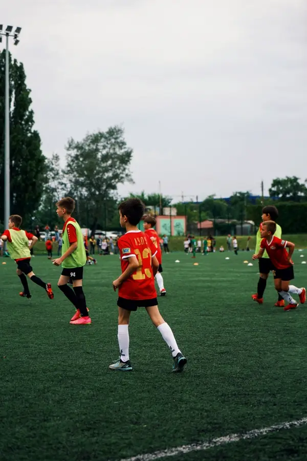 A young player controls the ball on a grass pitch